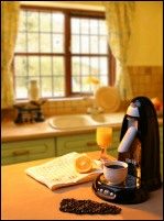 Coffee maker on table with coffee beans and orange juice set in kitchen environment.